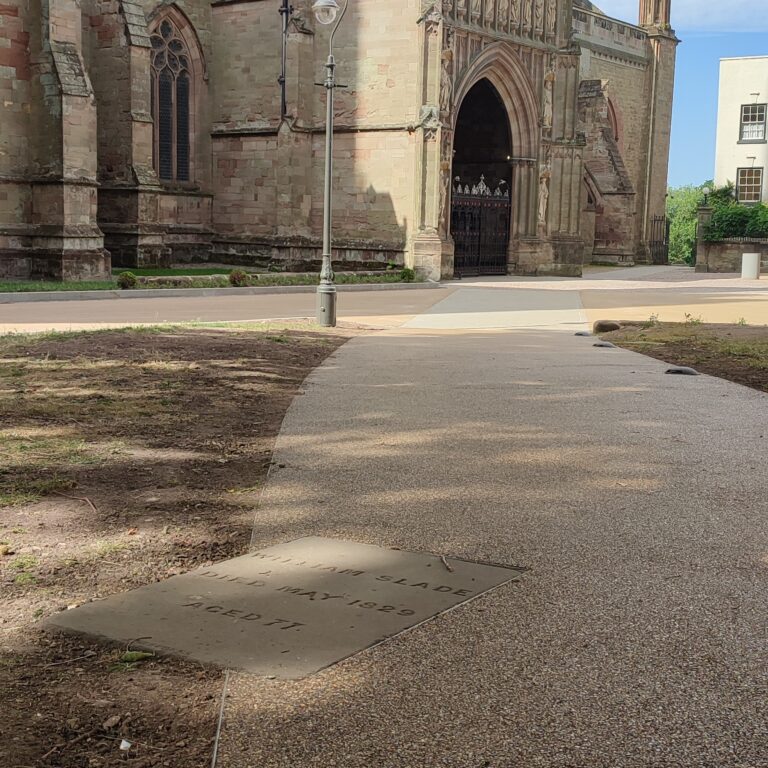 A stone path featuring the HALESTEM gravestone leads to a historic cathedral entrance, bordered by grass and dirt. A lamp post stands nearby under a partly cloudy sky.