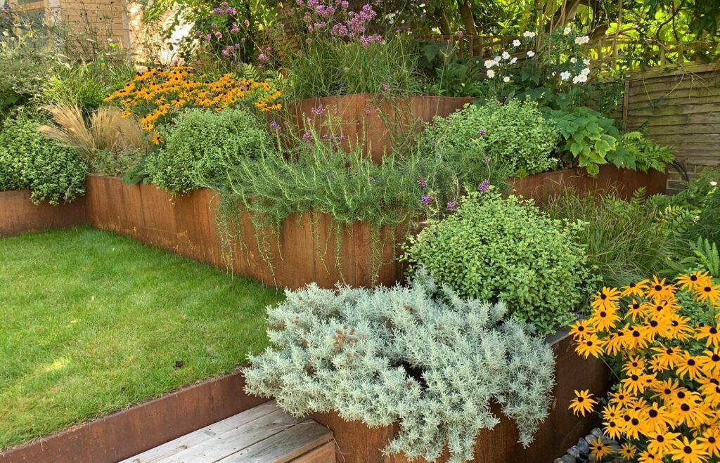 http://multiple%20height%20planters%20in%20corner%20of%20garden%20with%20trailing%20plants%20and%20shrubs.%20yellow%20and%20purple%20flowers