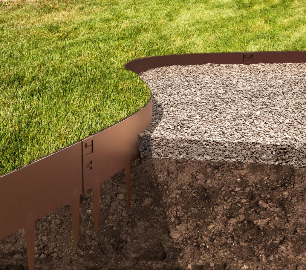A cross-section of a landscaped yard highlights metal lawn edging neatly separating green grass from a layer of gravel, with exposed soil beneath.